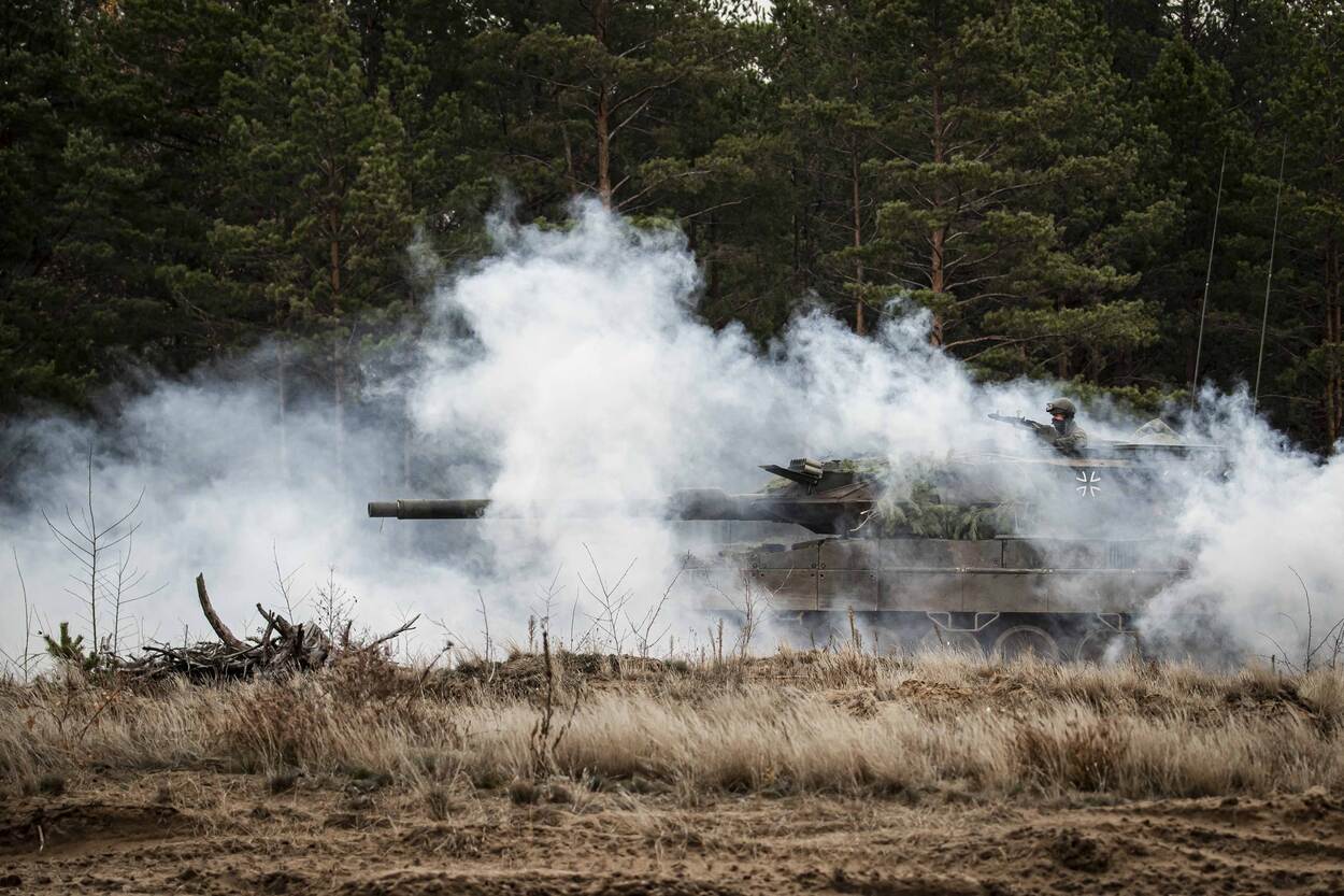 Foto ter illustratie van een Leopard 2a6-gevechtstank. Het voertuig draagt de Duitse vlag en is omgeven door rook.