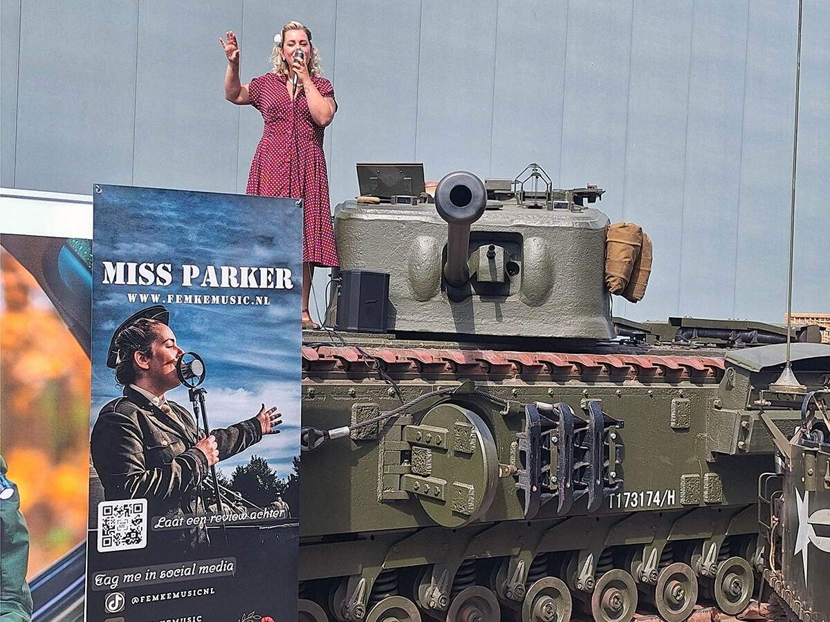 Zangeres Miss Parker staat op de tank te zingen met daarvoor een poster van het festival.