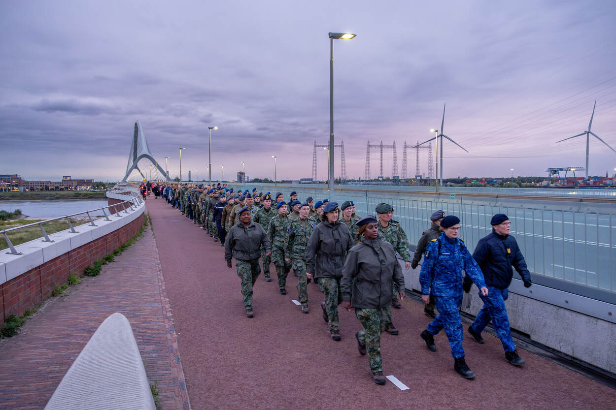 Militairen wandelen over een brug, vrouwen voorop