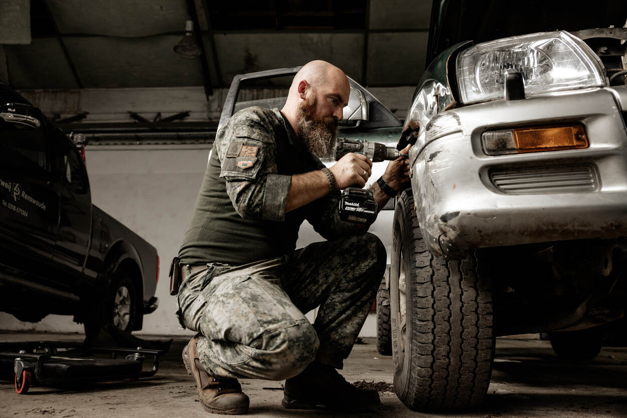 Een monteur sleutelt aan een voertuig