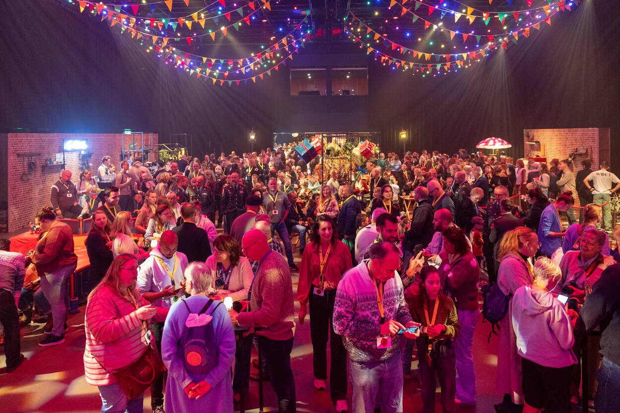 Feestelijk verlichte zaal vol mensen.