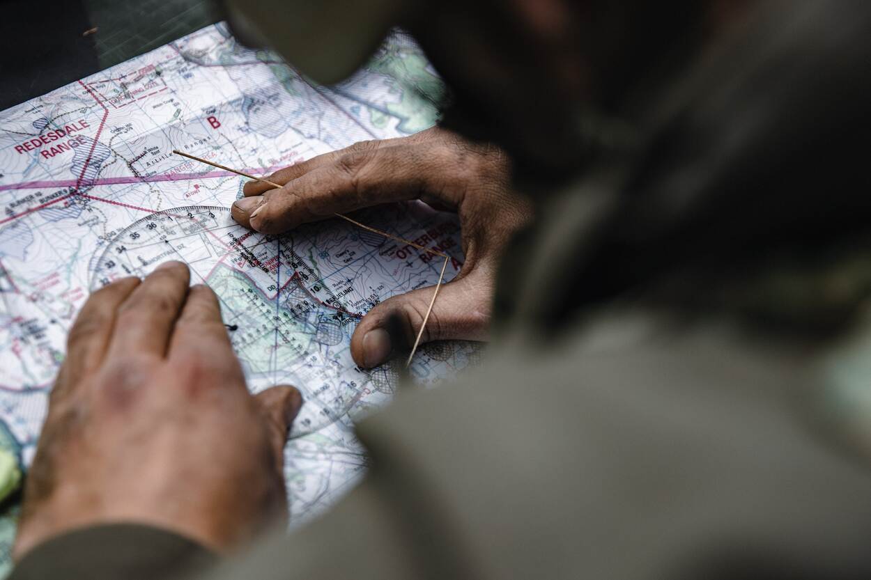 Een marinier bepaalt zijn positie met kaart en kompas.