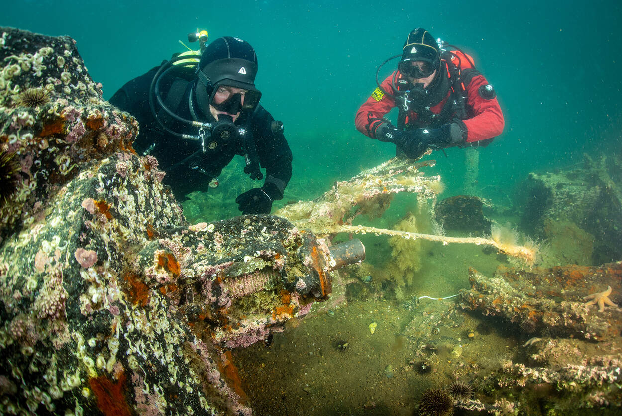 Robert Leenen en zijn vriend Anton van Rosmalen in duikerpak onder water bij de restanten van de Tirpitz.
