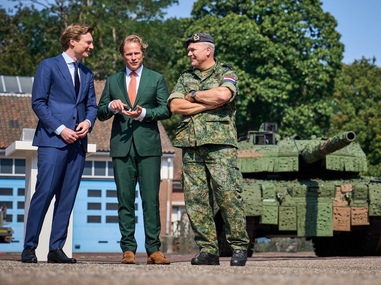 Minister Brekelmans, staatssecretaris Tuinman en CDS generaal Eichelsheim staan naast elkaar met een Leopard-tank op de achtergrond.