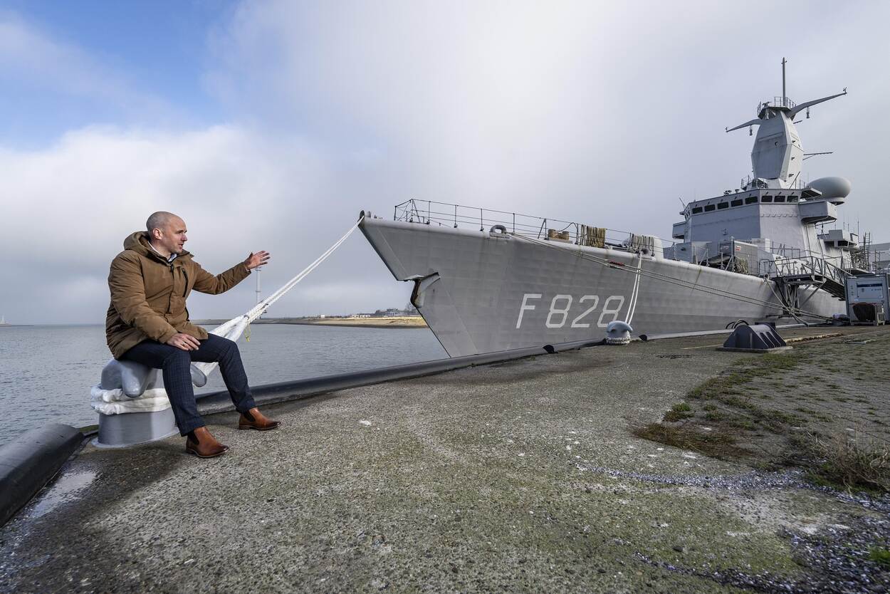 Cees van Rijn met op de achtergrond een marineschip dat aan de kade ligt.