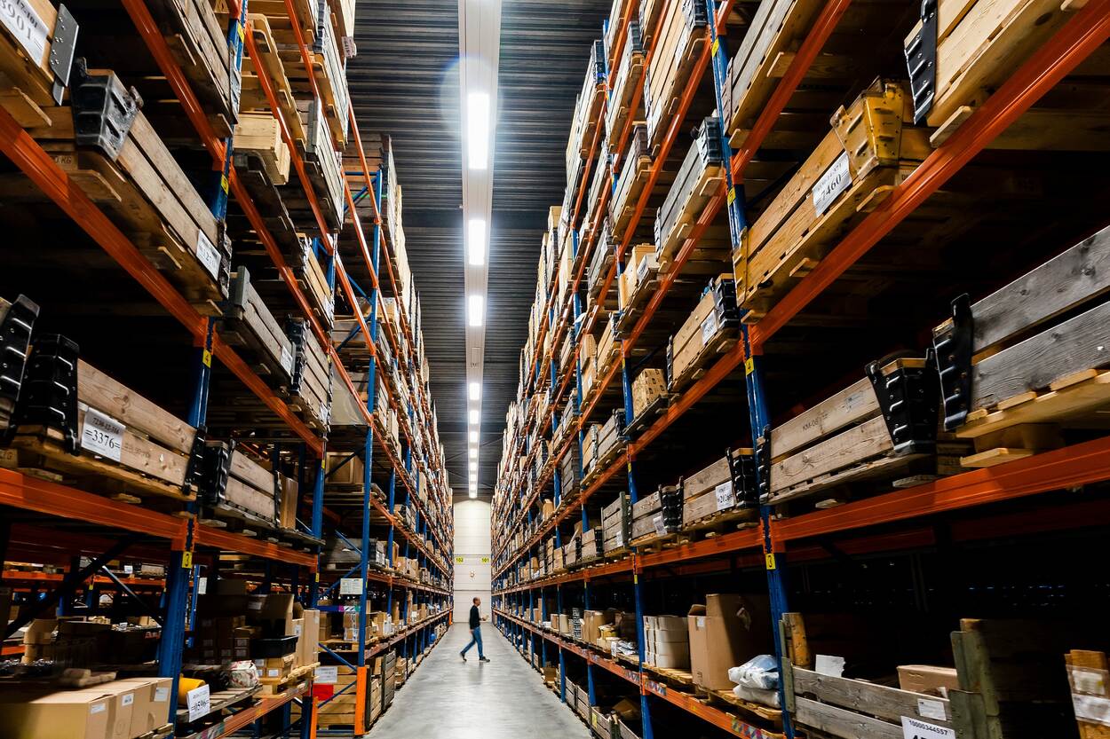 Een medewerker loopt door een groot magazijn van DMI.