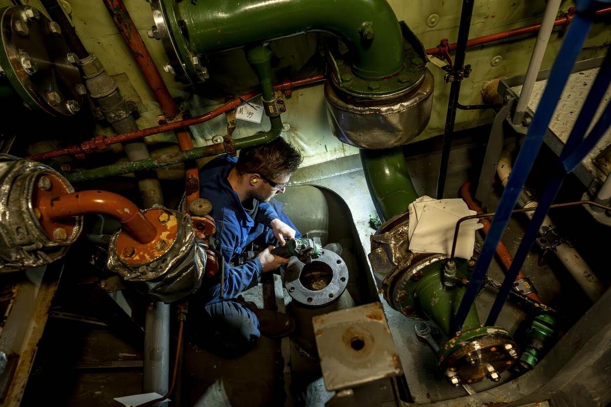 Een monteur aan het werk in het M-fregat Zr.Ms. Van Speijk.