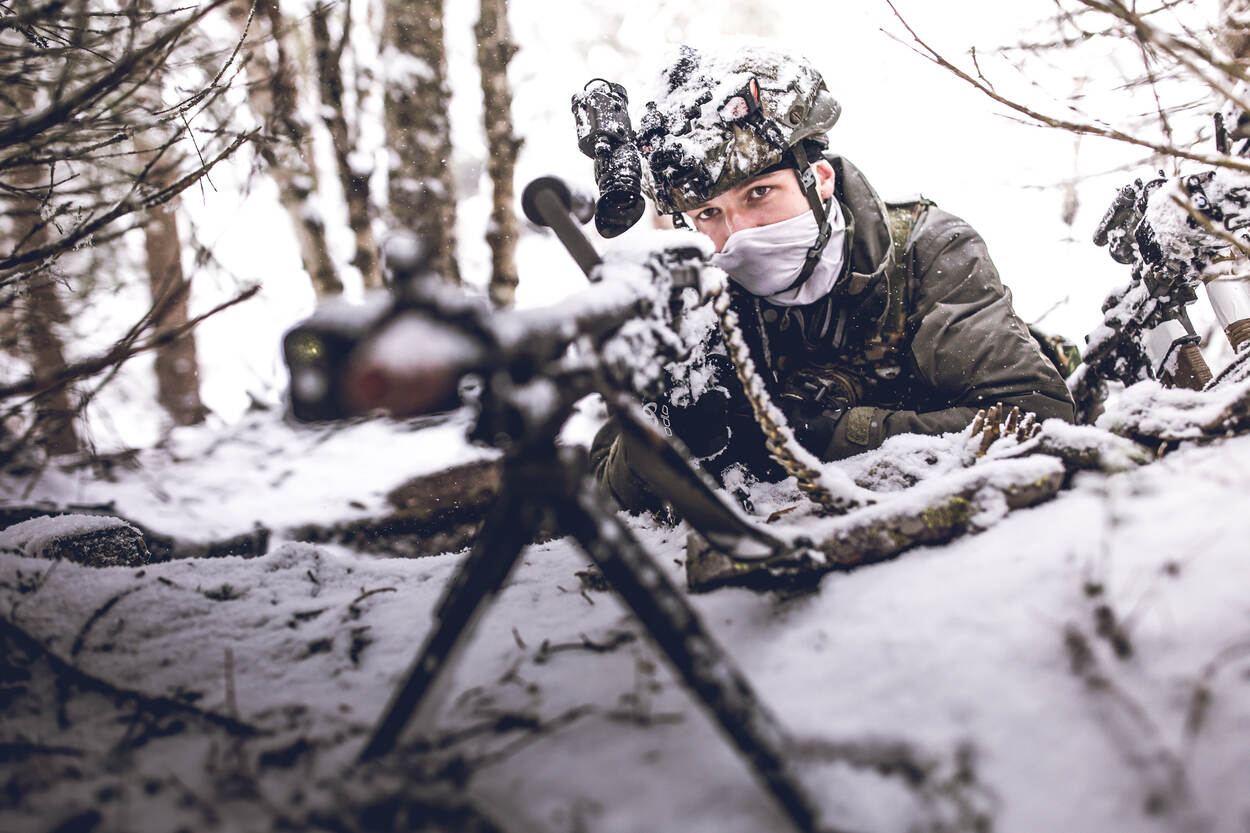 Een MAG-schutter liggend in de sneeuw.