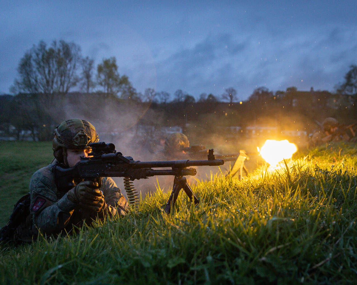 een militair bedient een machinegeweer.