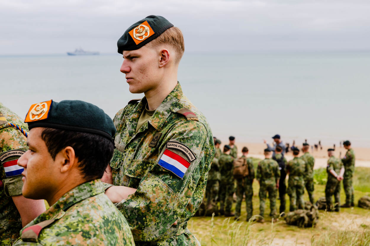 Een jonge fuselier kijkt en luistert naar een presentatie, terwijl op de achtergrond een andere groep een presentatie krijgt.