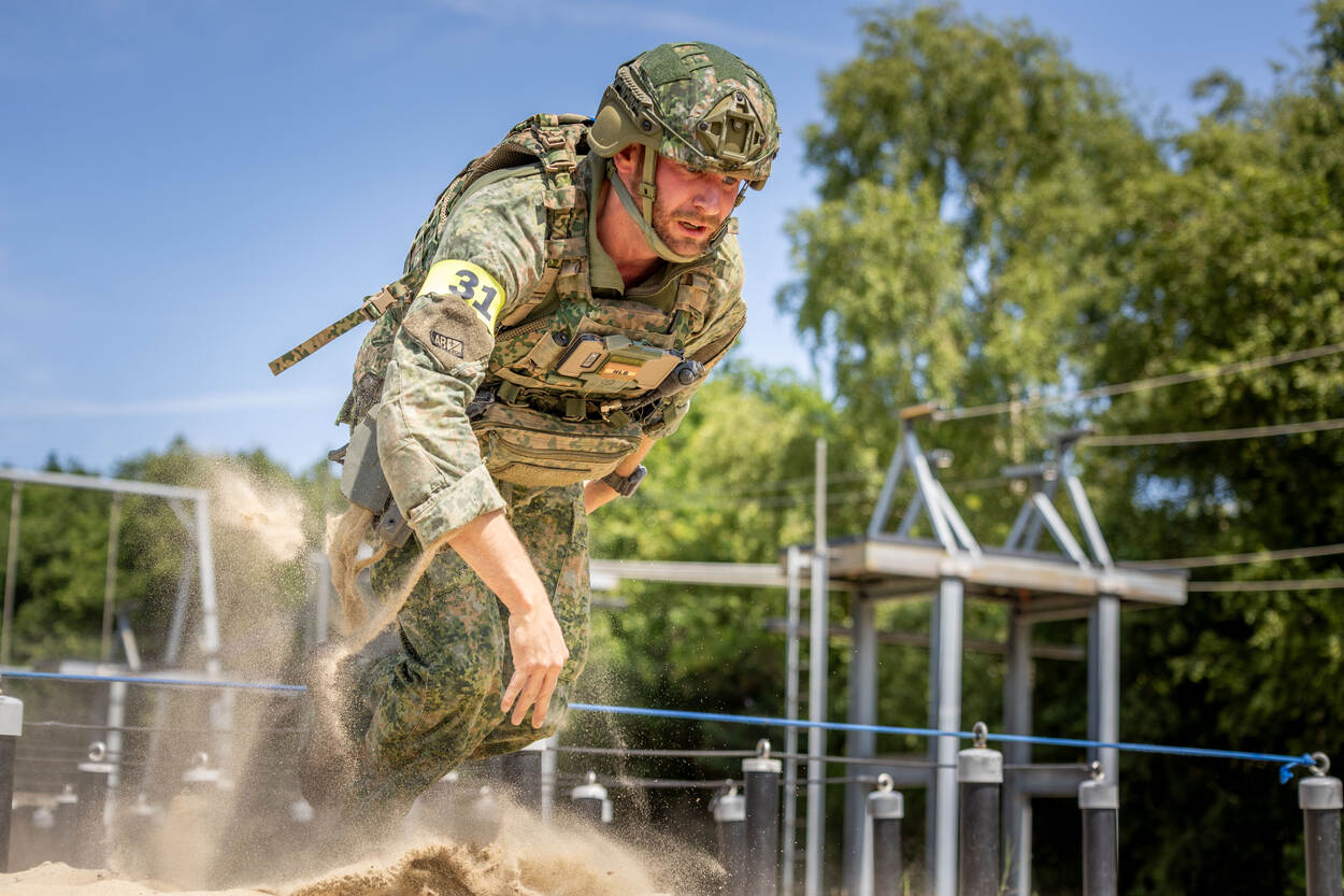 Een militair komt omhoog na een kruipoefening door het zand.