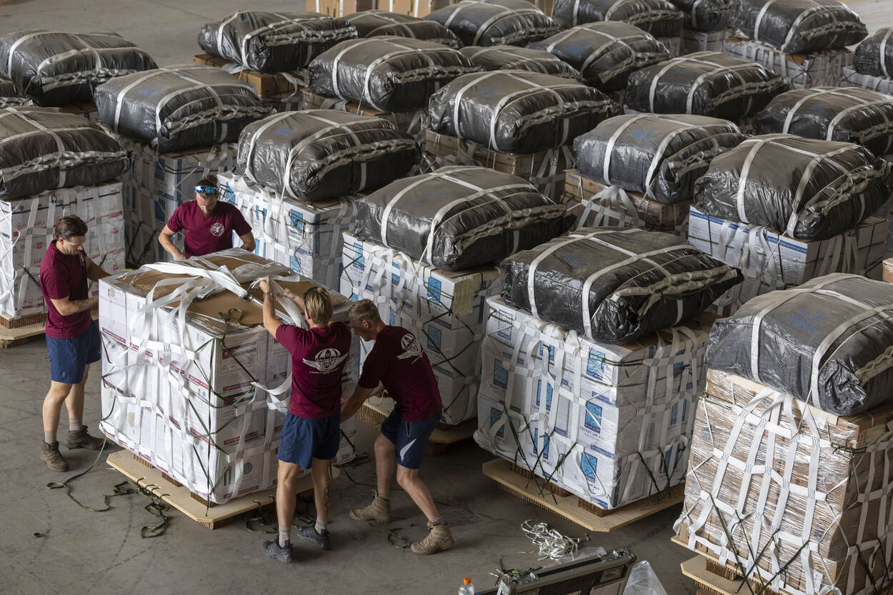 Militairen in rode shirts zijn bezig met het klaarmaken van een bundel noodgoederen.