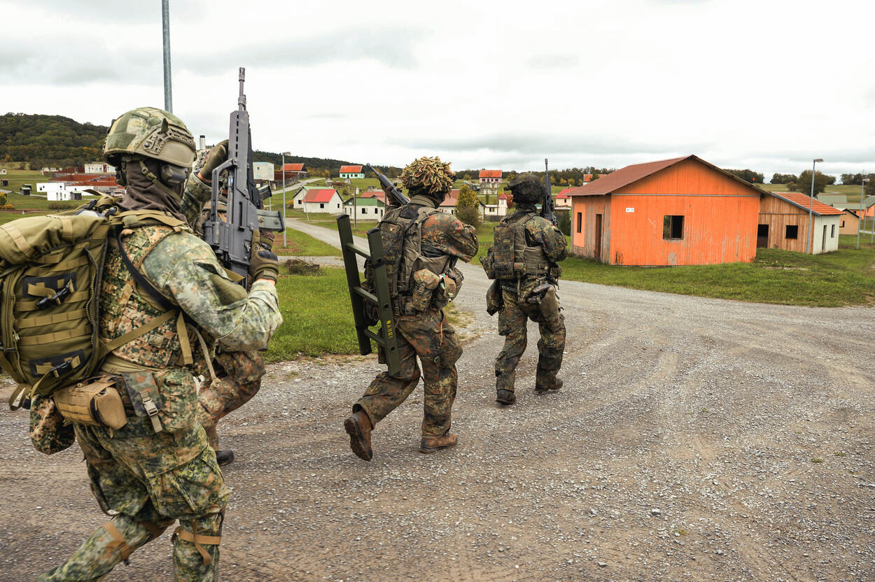 Militairen rennen naar een gebouw.