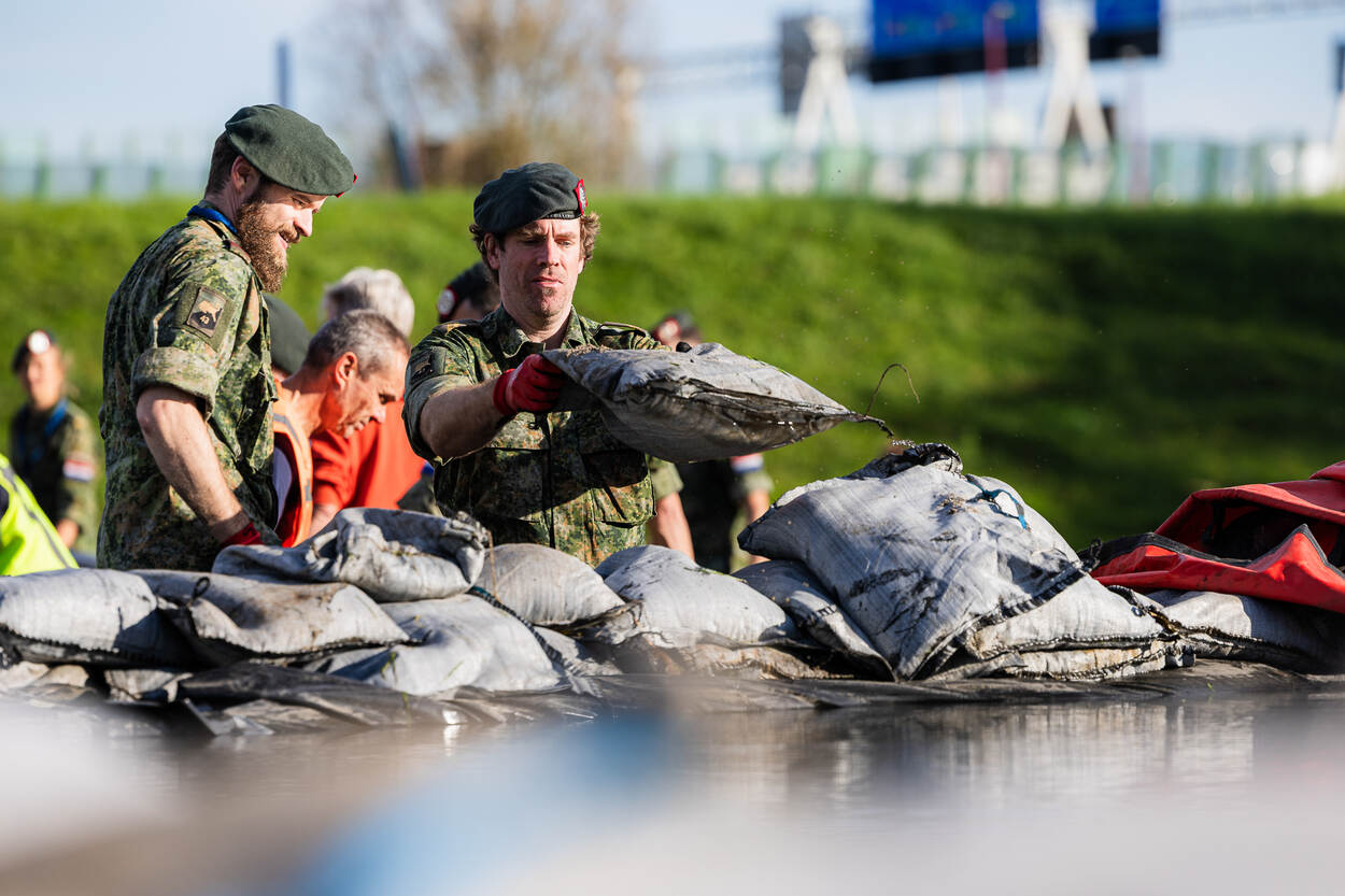 2 militairen leggen zandzakken neer.