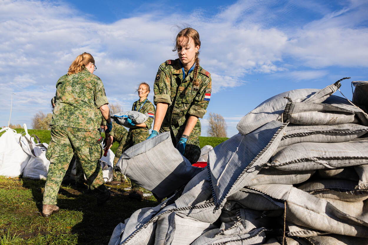 3 vrouwelijke militairen sjouwen met zandzakken.