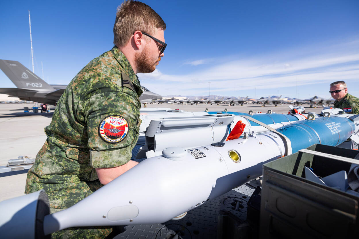 Twee militairen tillen een vliegtuigbom op.