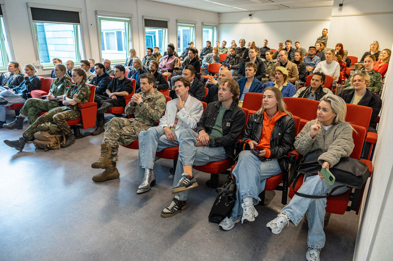 Artiesten en begeleiders luisteren aandachtig naar veiligheidsinstructies.
