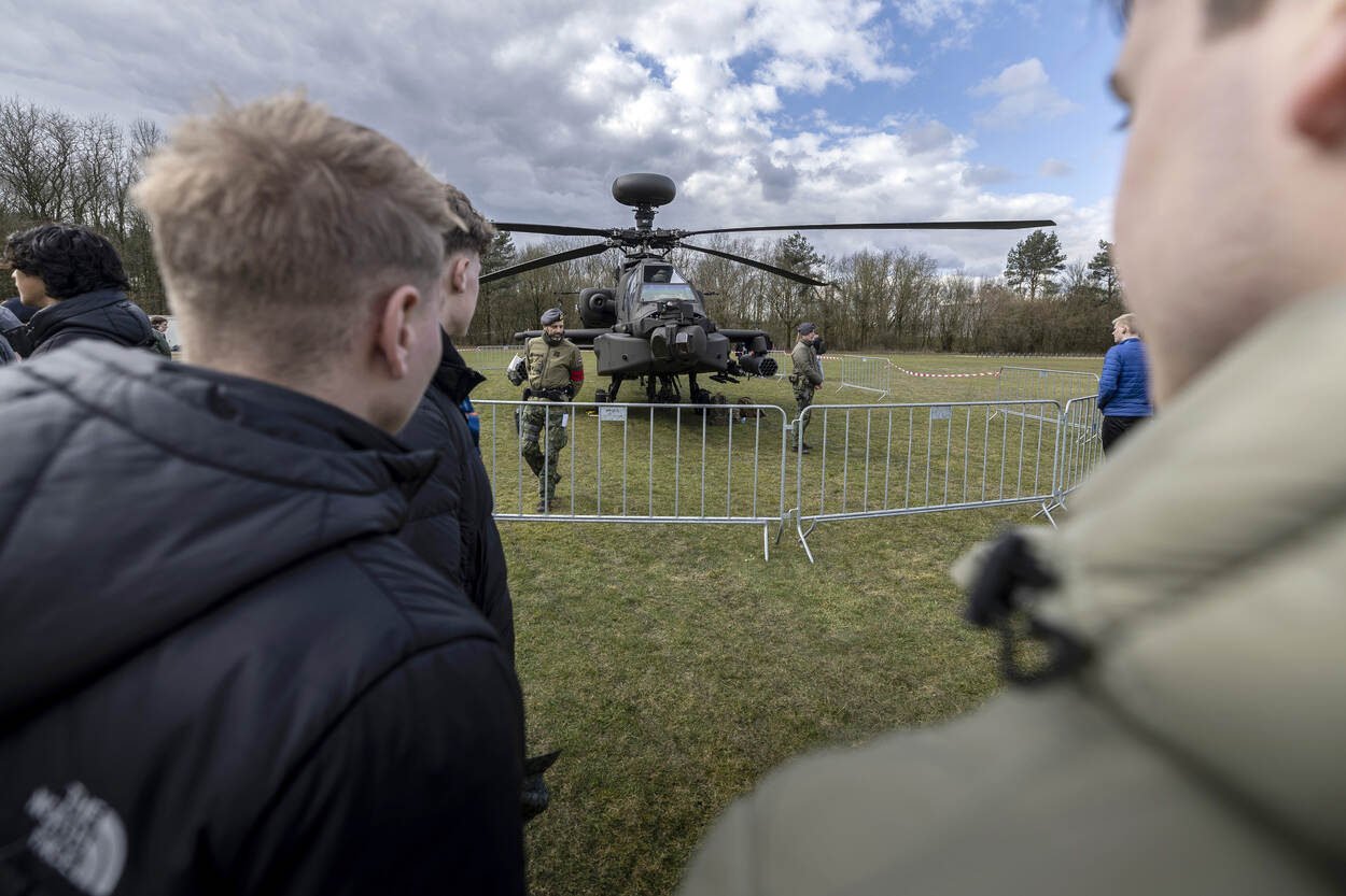 Jongeren kijken naar een Apache waarvoor een militair staat.