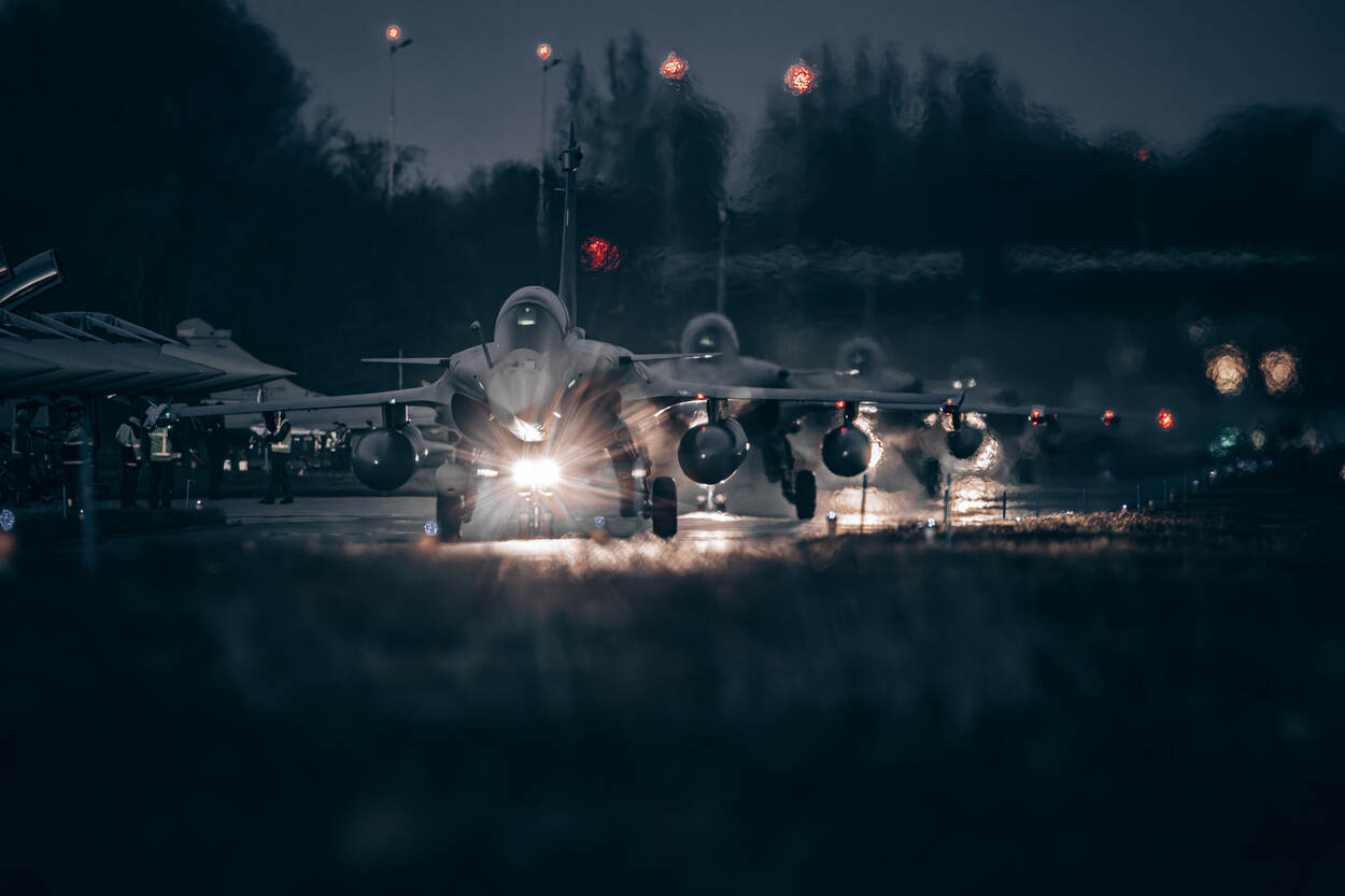 In het schemerdonker taxiën vier Rafales achter elkaar. Felle lampen schijnen vanaf hun landingsgestel op de taxibaan.