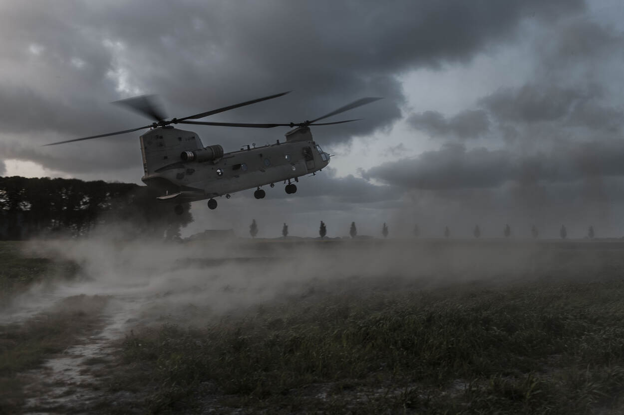 Landende Chinook met stofwolk in de schemer.