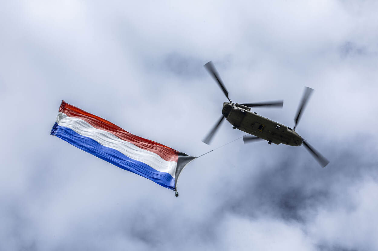Een gigantische Nederlandse vlag hangt onder een Chinook.