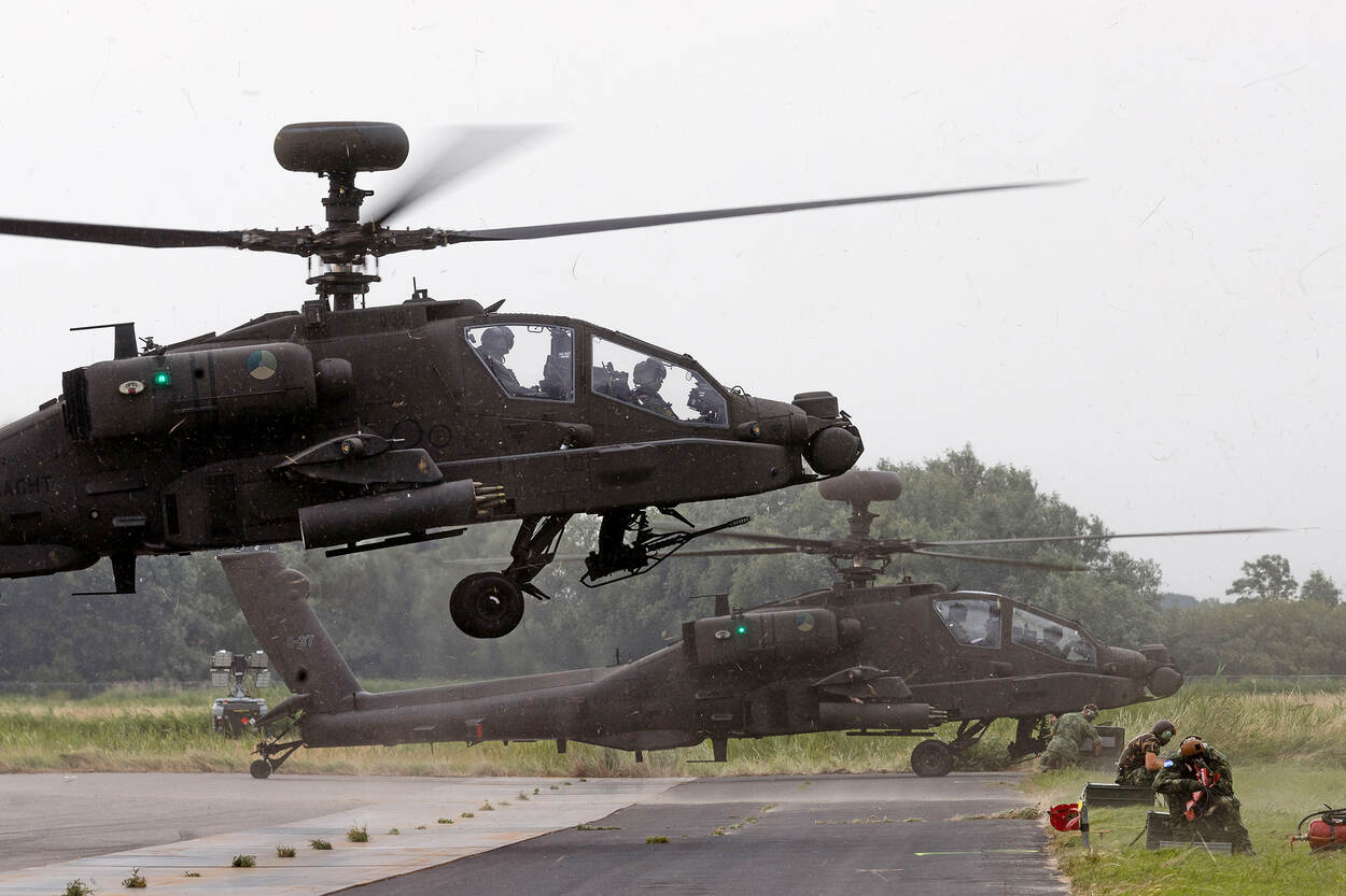 Gevechtshelikopter landt naast andere helikopter.