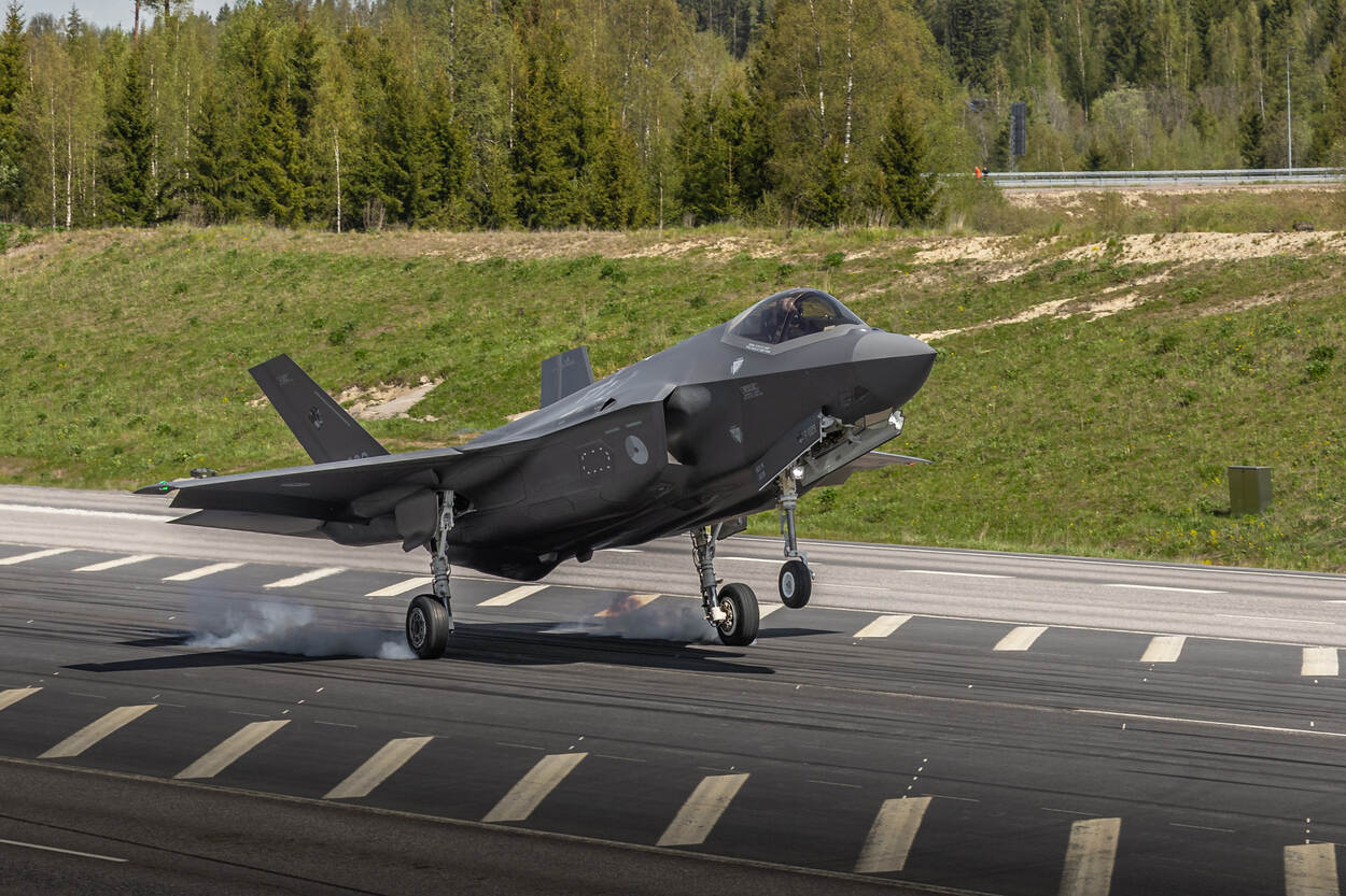 Een F-35 raakt met de wielen de snelweg waarbij stofwolken onder de wielen vandaan komen.