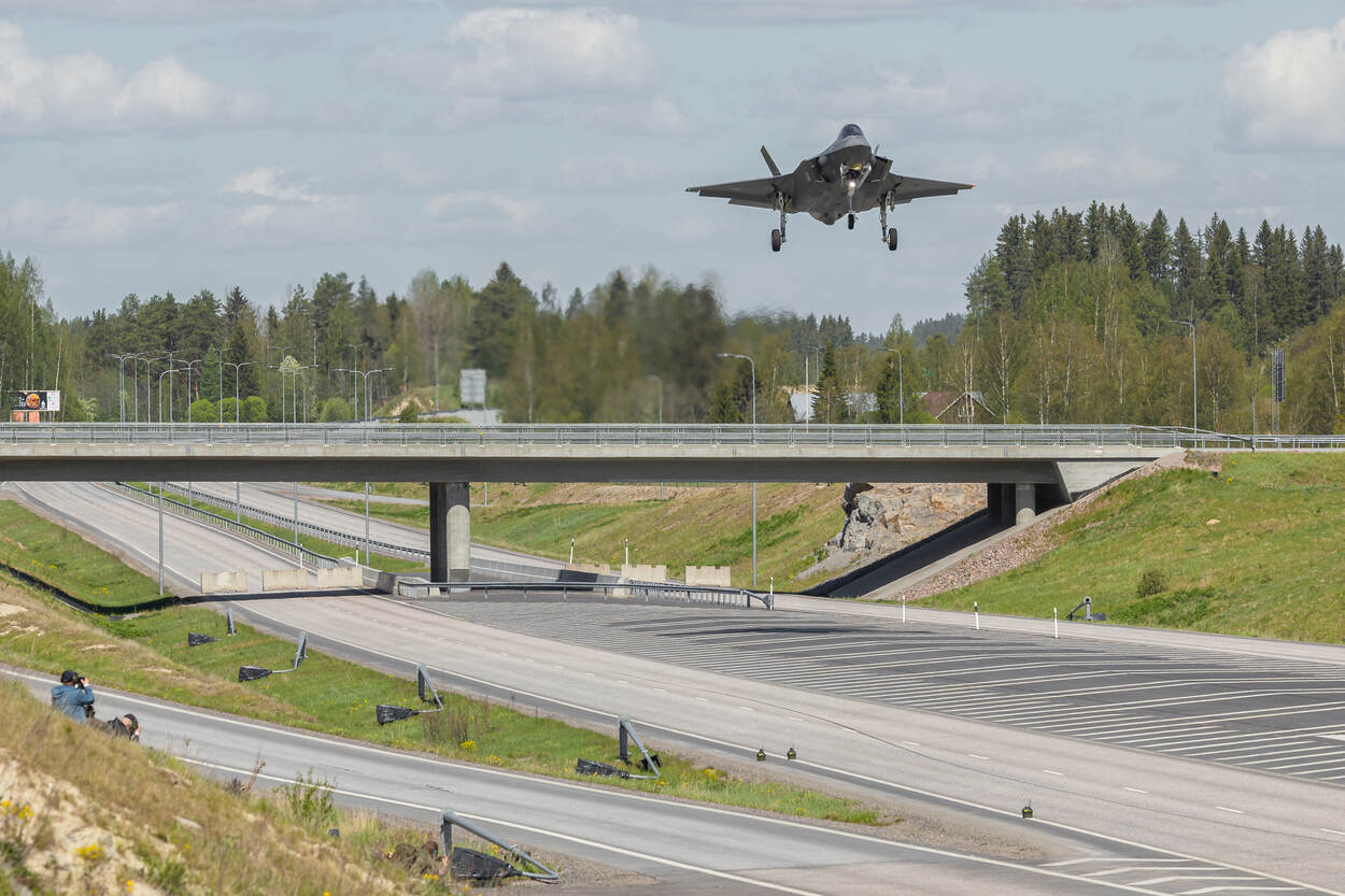 Een F-35 vliegt vlak boven een viaduct en snelweg.