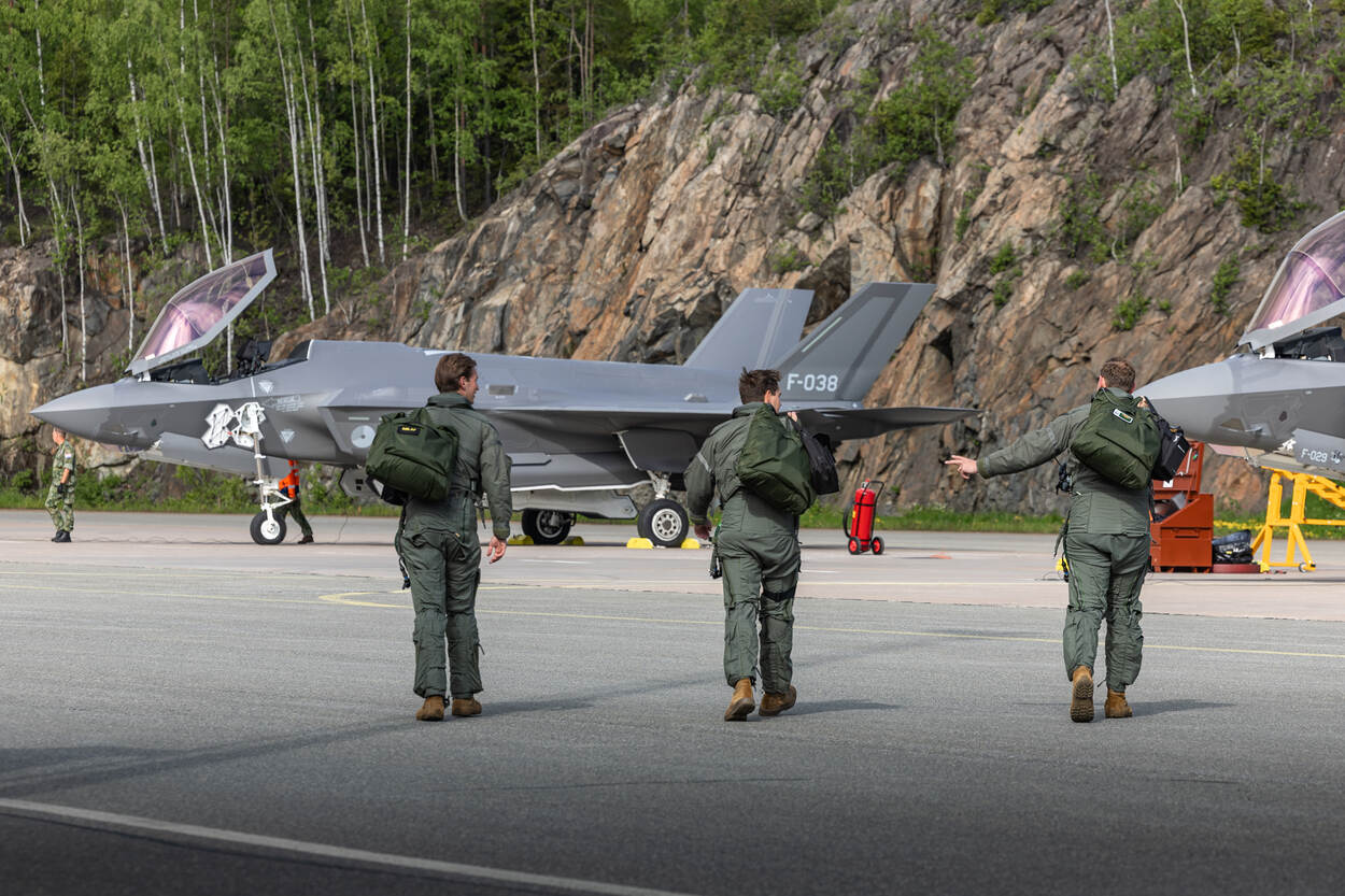 Drie vliegers lopen met hun tassen richting de F-35’s.