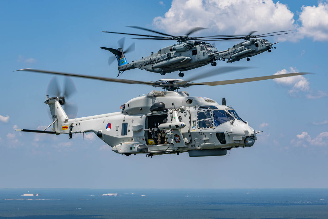 Een NH90 vliegt met twee CH-53E Super Stallions boven zee.