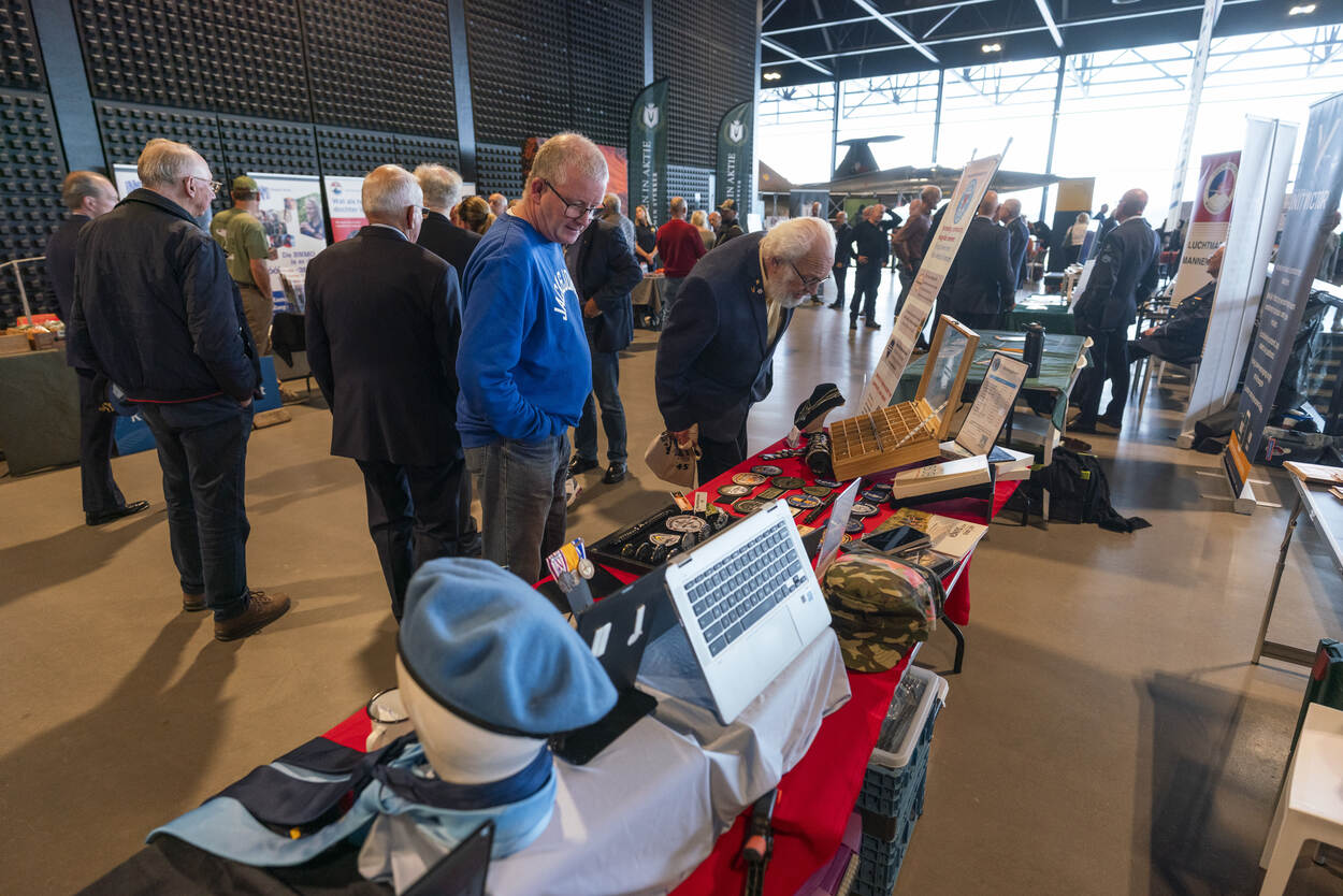 Bezoekers kijken bij uitgestalde waar op tafels.