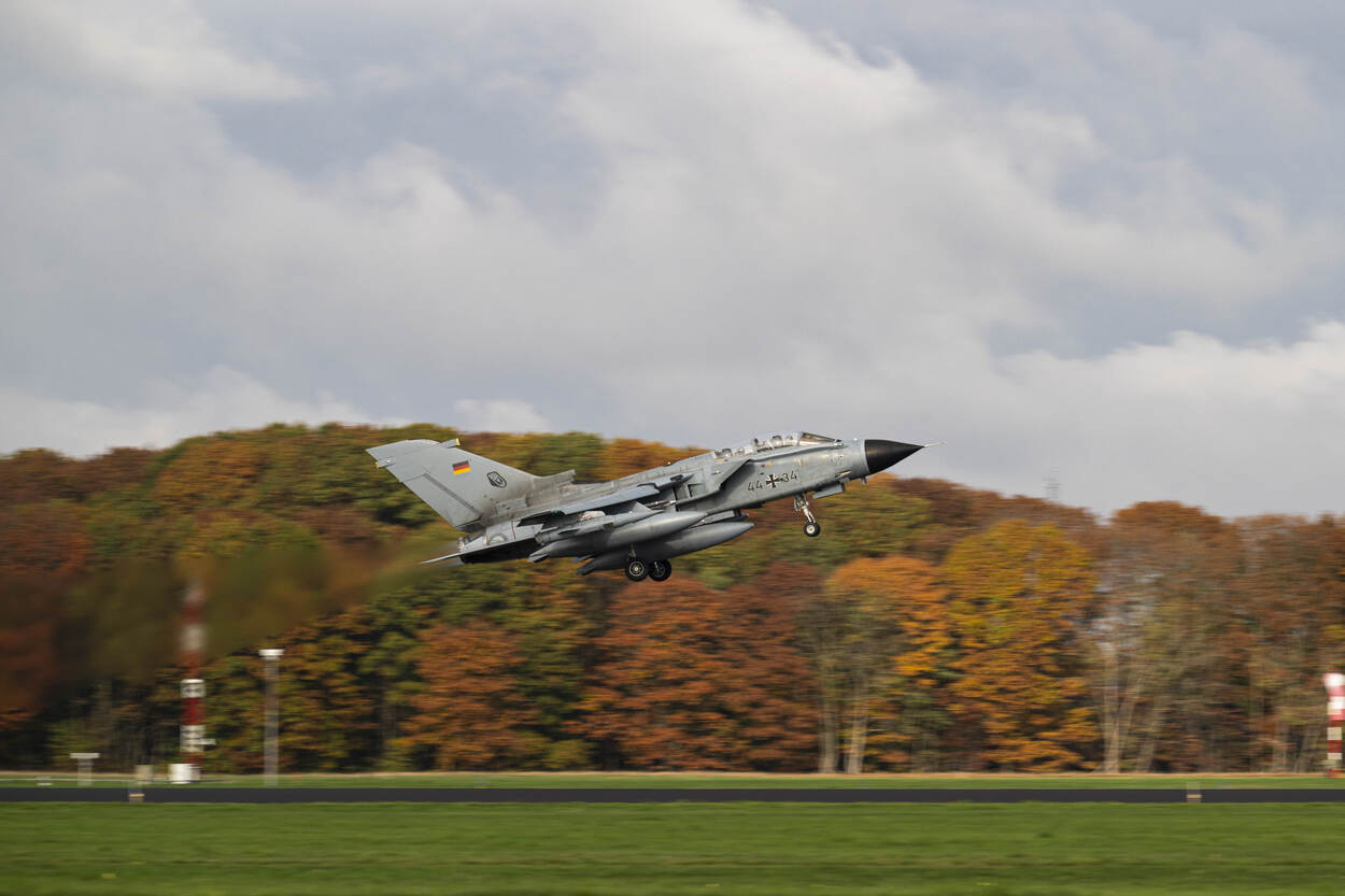 Een Tornado stijgt op tegen de achtergrond van een bos met herfstkleuren.