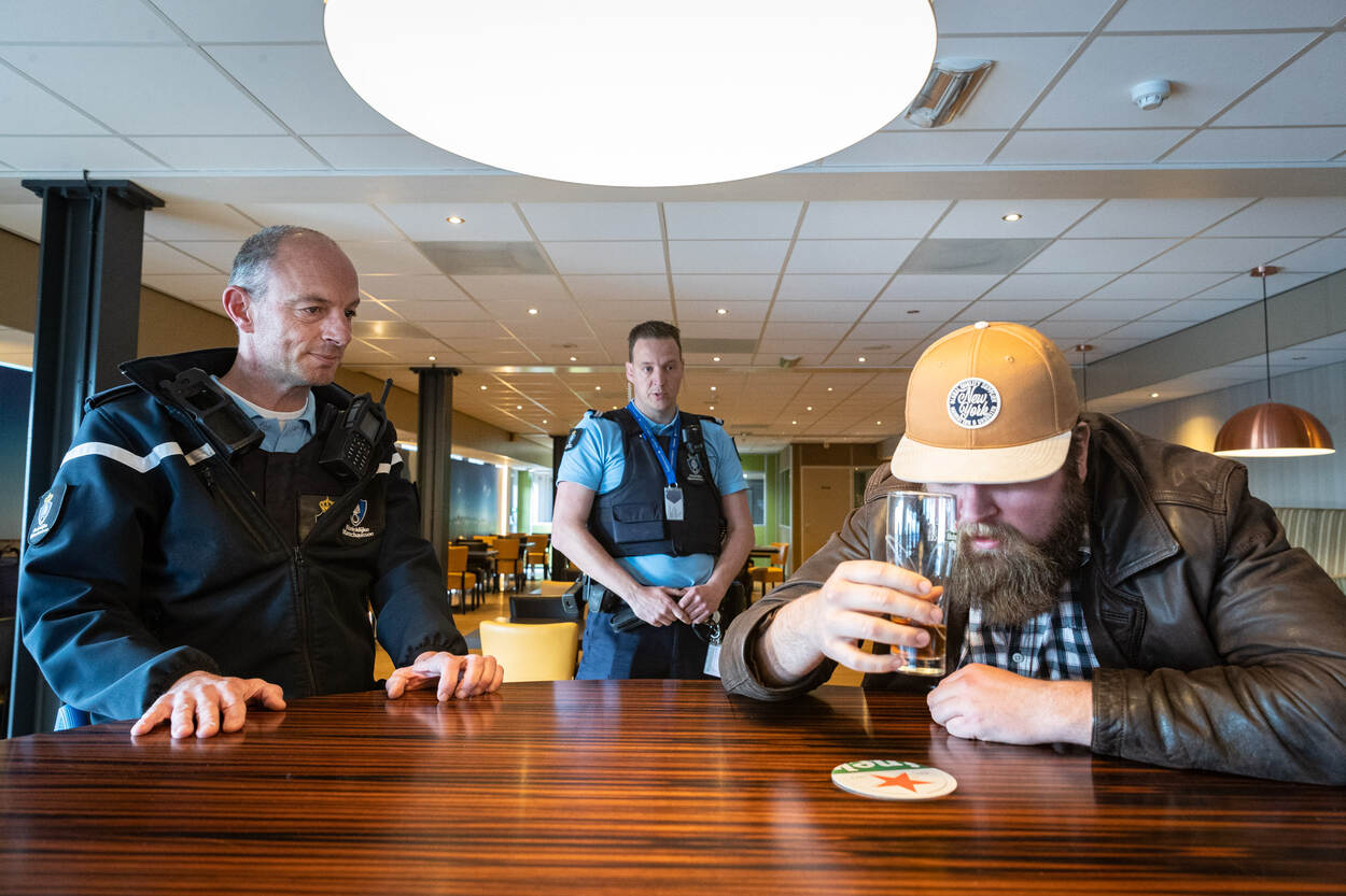 Een marechaussee benadert een dronken man.