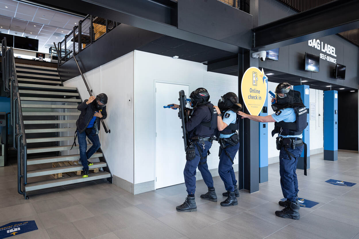 Marechaussees houden een verdachte onder schot die van de trap af strompelt.