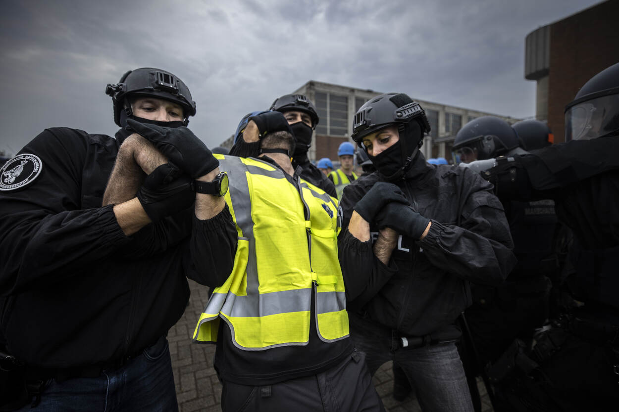 2 leden van de ME hebben een demonstrant vast aan zijn armen.