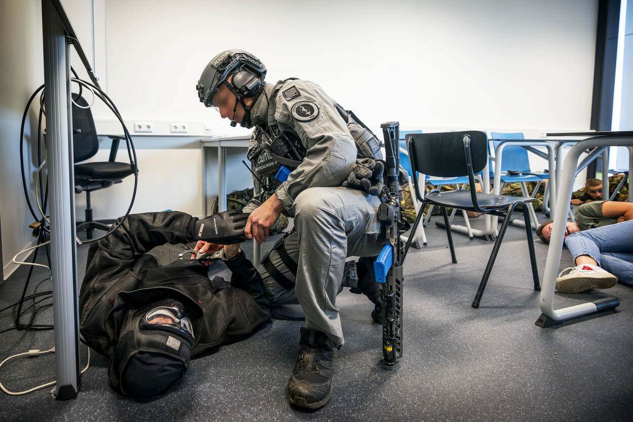 Een lid van het arrestatie- en ondersteuningsteam buigt zich over een van de daders.