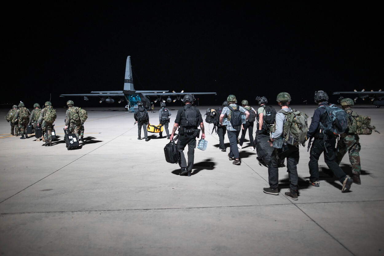 Evacuees worden naar een vliegtuig gebracht.