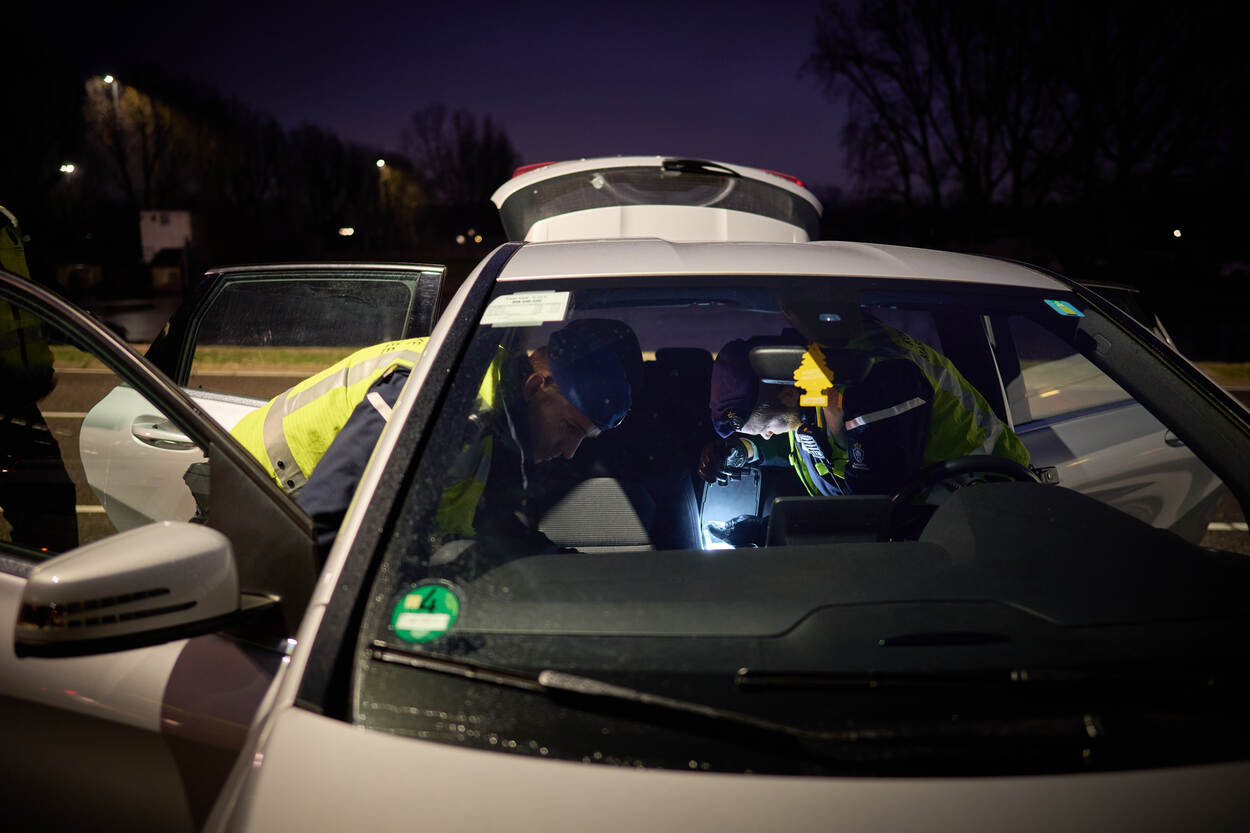 Twee marechaussees doorzoeken tegelijk binnenkant van een wagen.