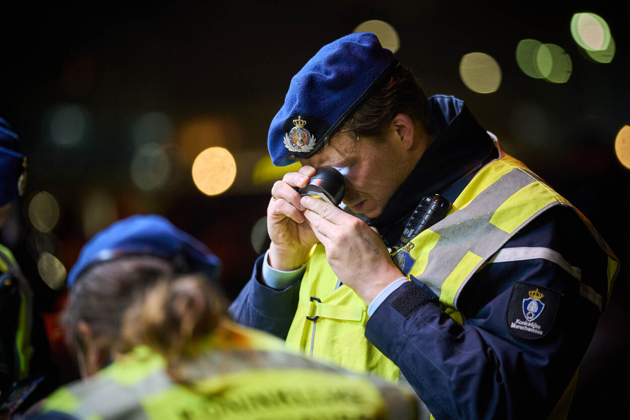 Marechaussee bekijkt met een loep een identiteitsbewijs.