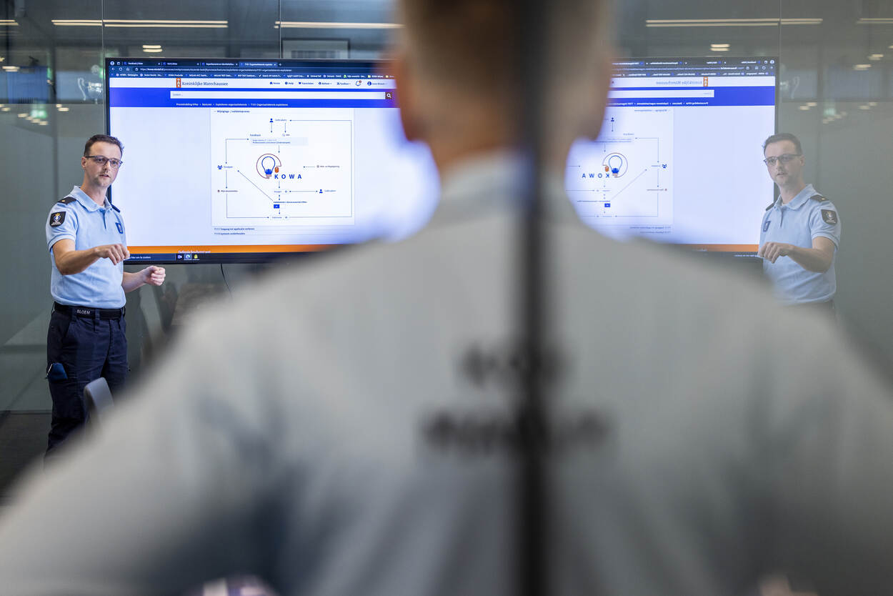 Een adjudant van de KMar voor een beeldscherm met daarop een afbeelding van KOWA.