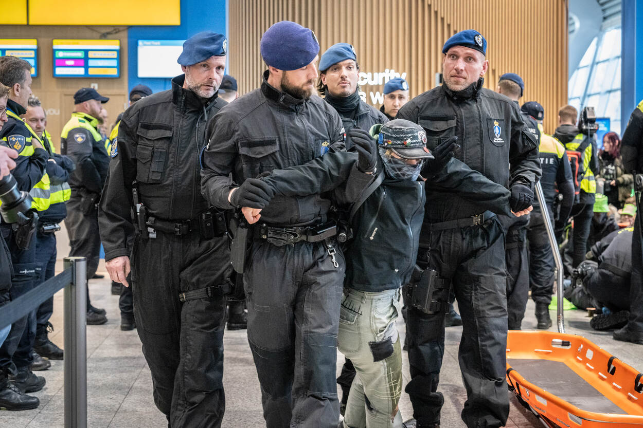 Collega’s van de Marechaussee verwijderen een actievoerder van Extinction Rebellion op Eindhoven Airport.