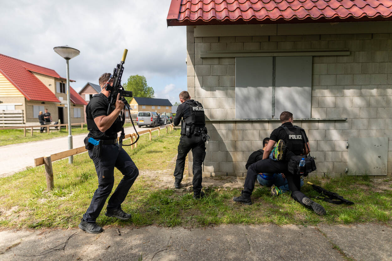 Persoonsbeveiligers zoeken tijdens een actie dekking achter een gebouw.