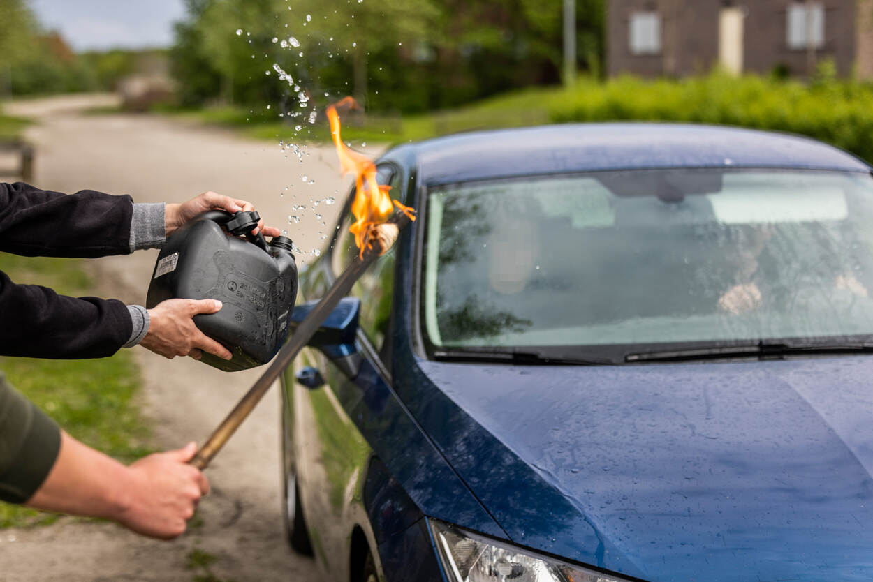 Boze omstanders belagen een auto met een fakkel.