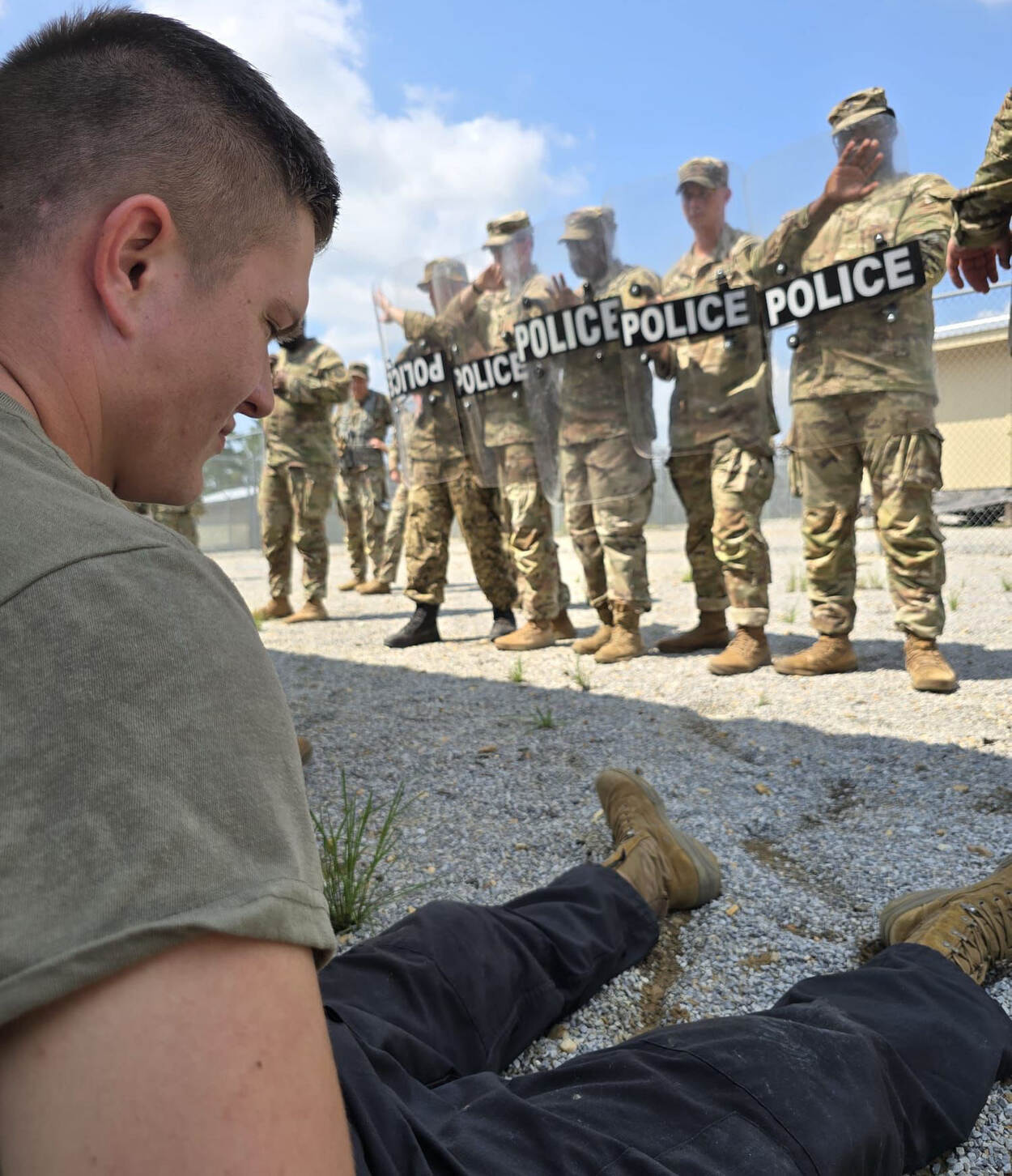 een arrestant zit op de grond tegenover leden van militaire politie