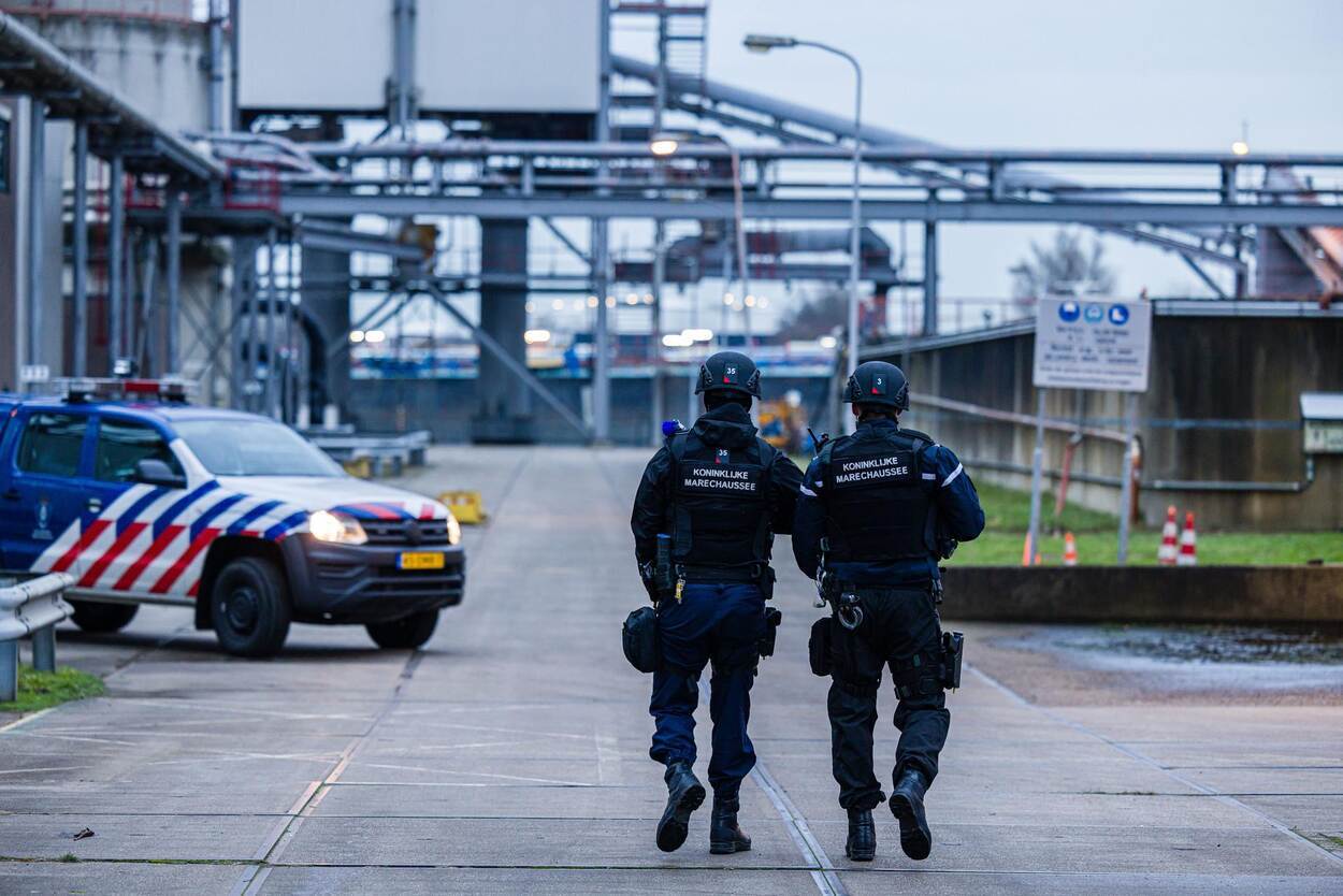 Twee marechaussees lopen over een fabrieksterrein.