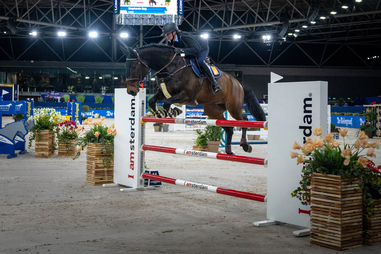 Opperwachtmeester Stephanie en Luxor springen over een hindernis met rood-witte palen.
