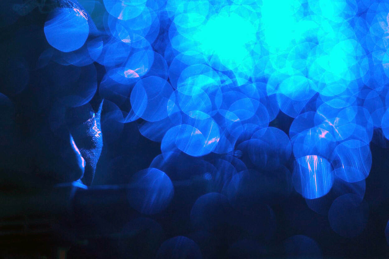 Close-up van collega terwijl blauw zwaailicht weerkaatst in regendruppels.