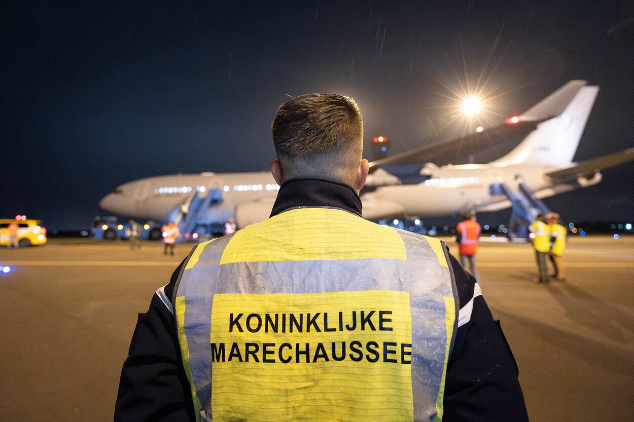 Een marechaussee met hesje voor een vliegtuig op Schiphol.