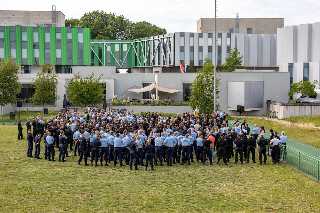 Een grote groep marechaussees luistert naar een toespraak van de commandant.