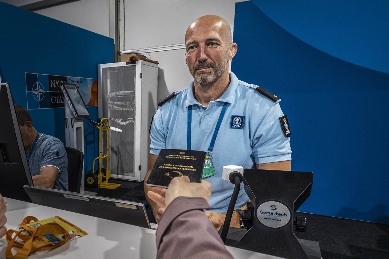 Een marechaussee controleert een document van een reiziger.